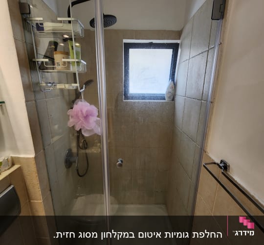 מקלחת עם מדף מוצרים, ראש מקלחת וחלון קטן